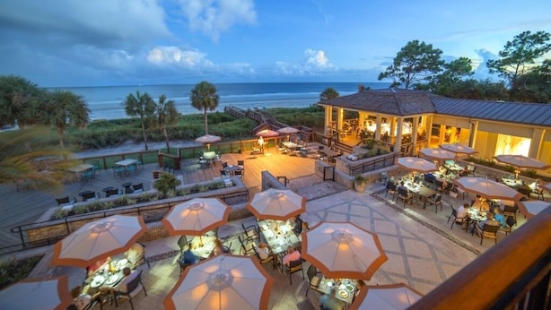 Un espace de restauration en plein air, agrémenté de parasols et de tables, avec vue sur la plage.
