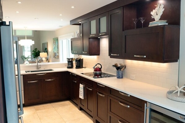 Una cocina moderna con gabinetes de madera oscura, una encimera blanca y una estufa empotrada.