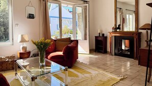 Un salon avec une table basse en verre, un canapé rouge et une cheminée.