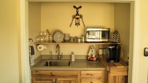 A compact kitchen with a stainless steel sink, a microwave, and a coffee maker. - Kiler Studio Apartment is a relaxing and charming wine country getaway for two! (Paso Robles)