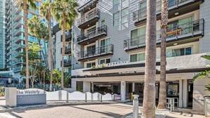 A modern hotel with a sign reading "The Westerly on Lincoln." It features a brick-paved entrance, palm trees, and a multi-story building with balconies.