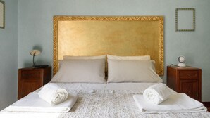 Ein Hotelzimmer mit einem großen Bett, zwei Nachttischen und einem goldgerahmten Kopfteil.