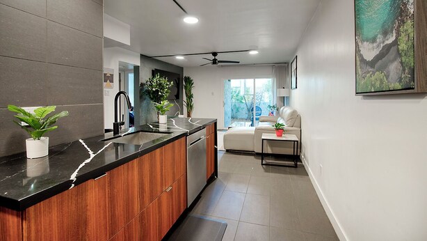A modern kitchen with a black countertop, wooden cabinets, and a built-in dishwasher. There is a ceiling fan and recessed lighting. - Cozy 2-bedroom condo in terrific Old Town Scottsdale with WiFi, AC, and patio (Scottsdale)
