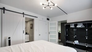 A modern bedroom with a bed, a wardrobe with a mirror, a black shelving unit, and a ceiling light fixture. - Cozy 2-bedroom condo in terrific Old Town Scottsdale with WiFi, AC, and patio (Scottsdale)