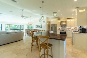 A spacious kitchen with a central island, modern appliances, and a dining area with a sofa and chairs. - Camino Del Mar - Steps from the Beach! (Sanibel)