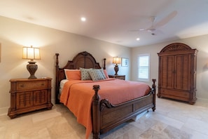 A bedroom with a large bed, two nightstands, a wardrobe, and a ceiling fan. - Camino Del Mar - Steps from the Beach! (Sanibel)