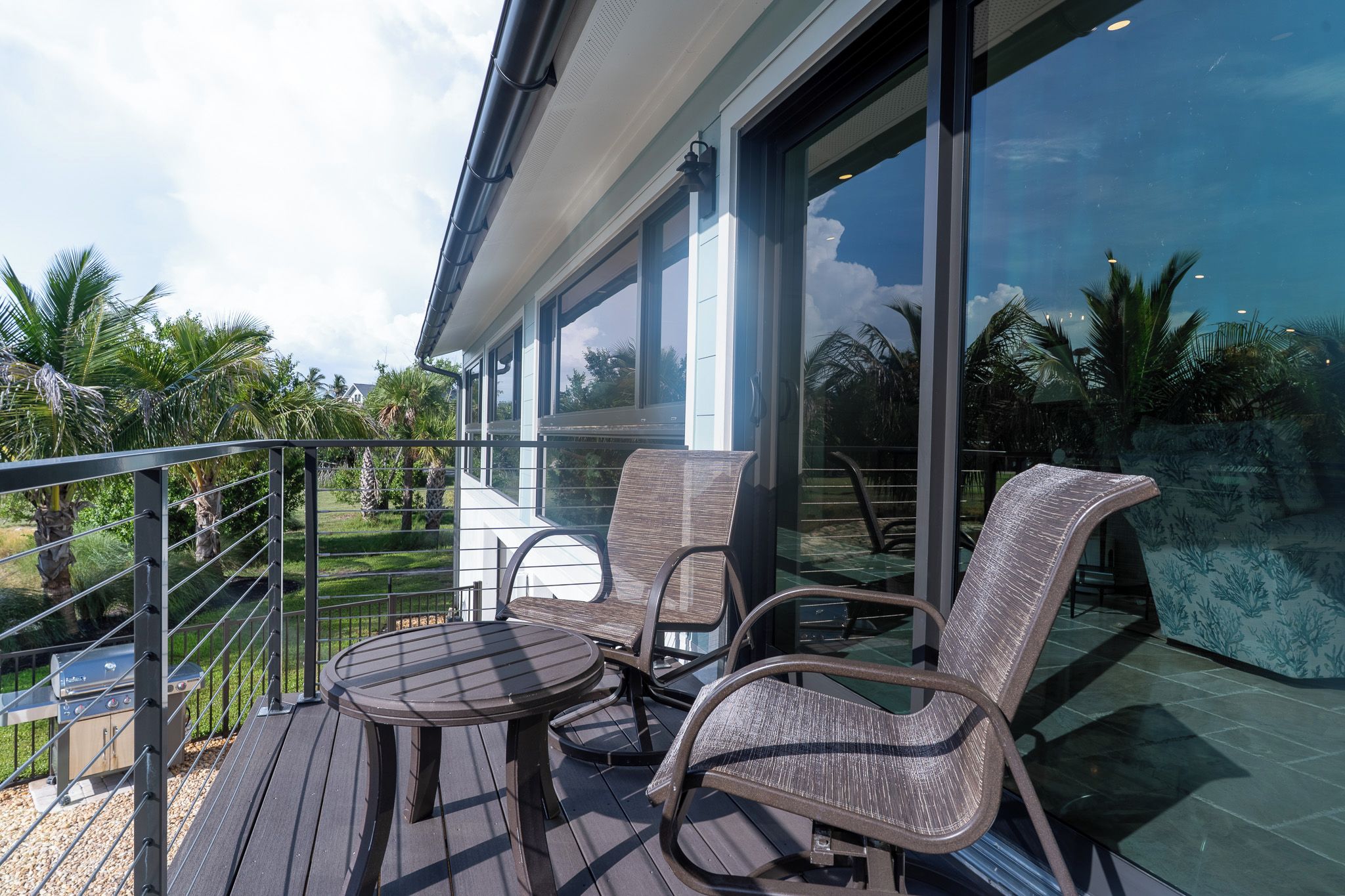 A balcony with outdoor furniture, a grill, and a view of the surrounding landscape.