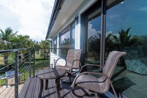 A balcony with outdoor furniture, a grill, and a view of the surrounding landscape. - Camino Del Mar - Steps from the Beach! (Sanibel)