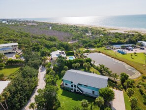 A coastal property with multiple buildings, a swimming pool, and a beach. - Camino Del Mar - Steps from the Beach! (Sanibel)