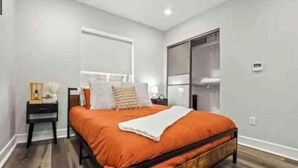 Un dormitorio con cama, mesita de noche y ventana.