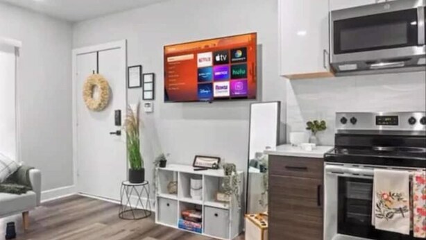 Una cocina moderna con horno empotrado, microondas y televisor de pantalla plana montado en la pared.