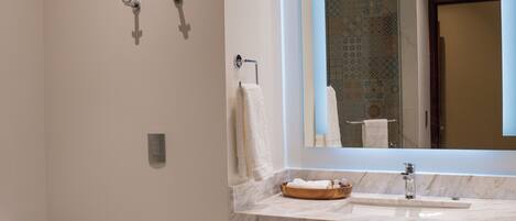 Un baño moderno con inodoro, lavabo de encimera de mármol, espejo y toallero.