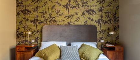A bed with a headboard, two bedside tables, and a patterned wall.