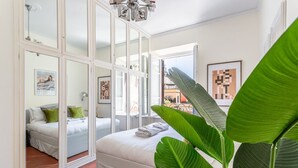 Een slaapkamer met een bed, een raam en een grote plant.