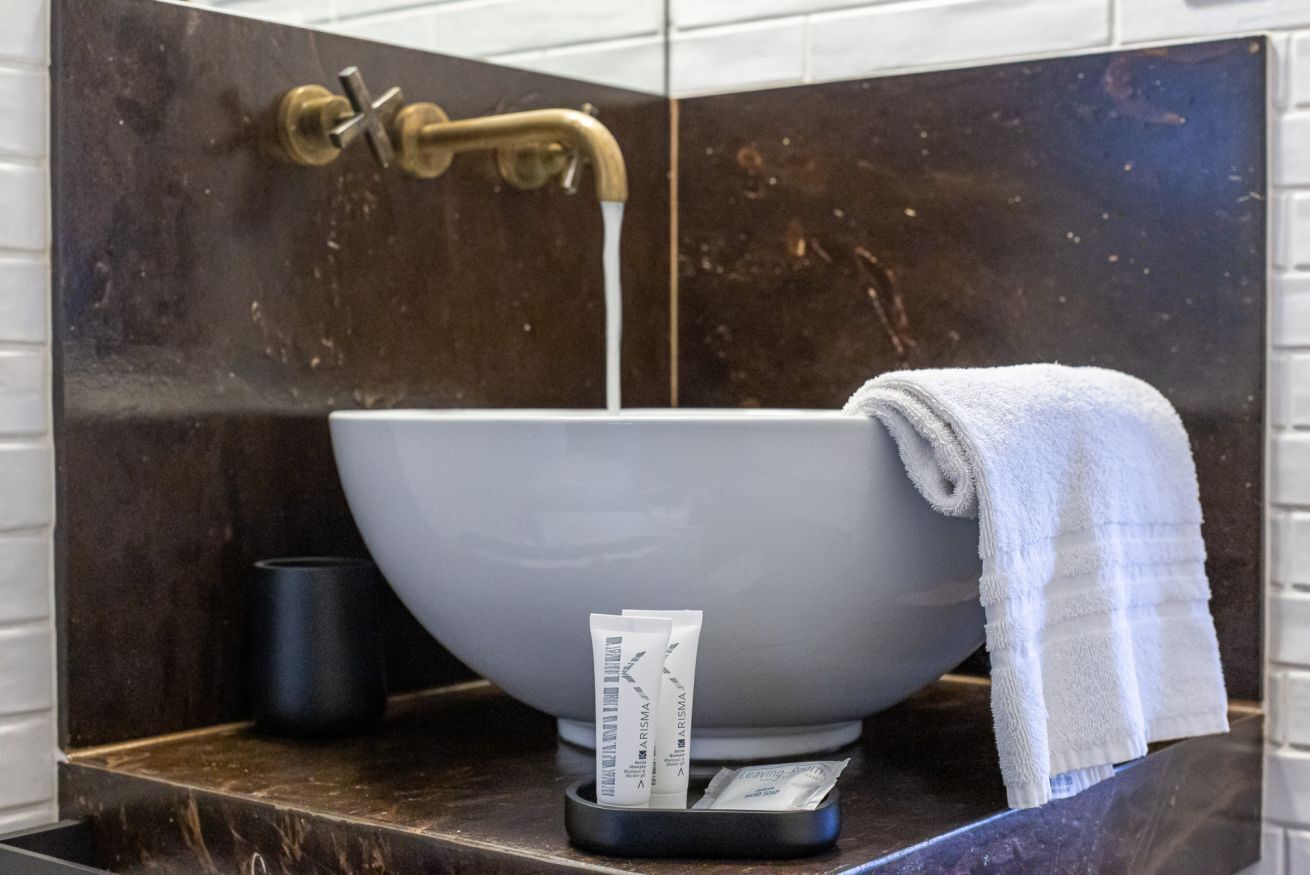 A bathroom with a white sink, a towel, and toiletries.