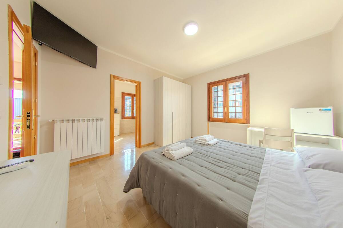 Ein Hotelzimmer mit einem großen Bett, einem Schreibtisch, einem Sessel, einem Fernseher und einem Kleiderschrank.
