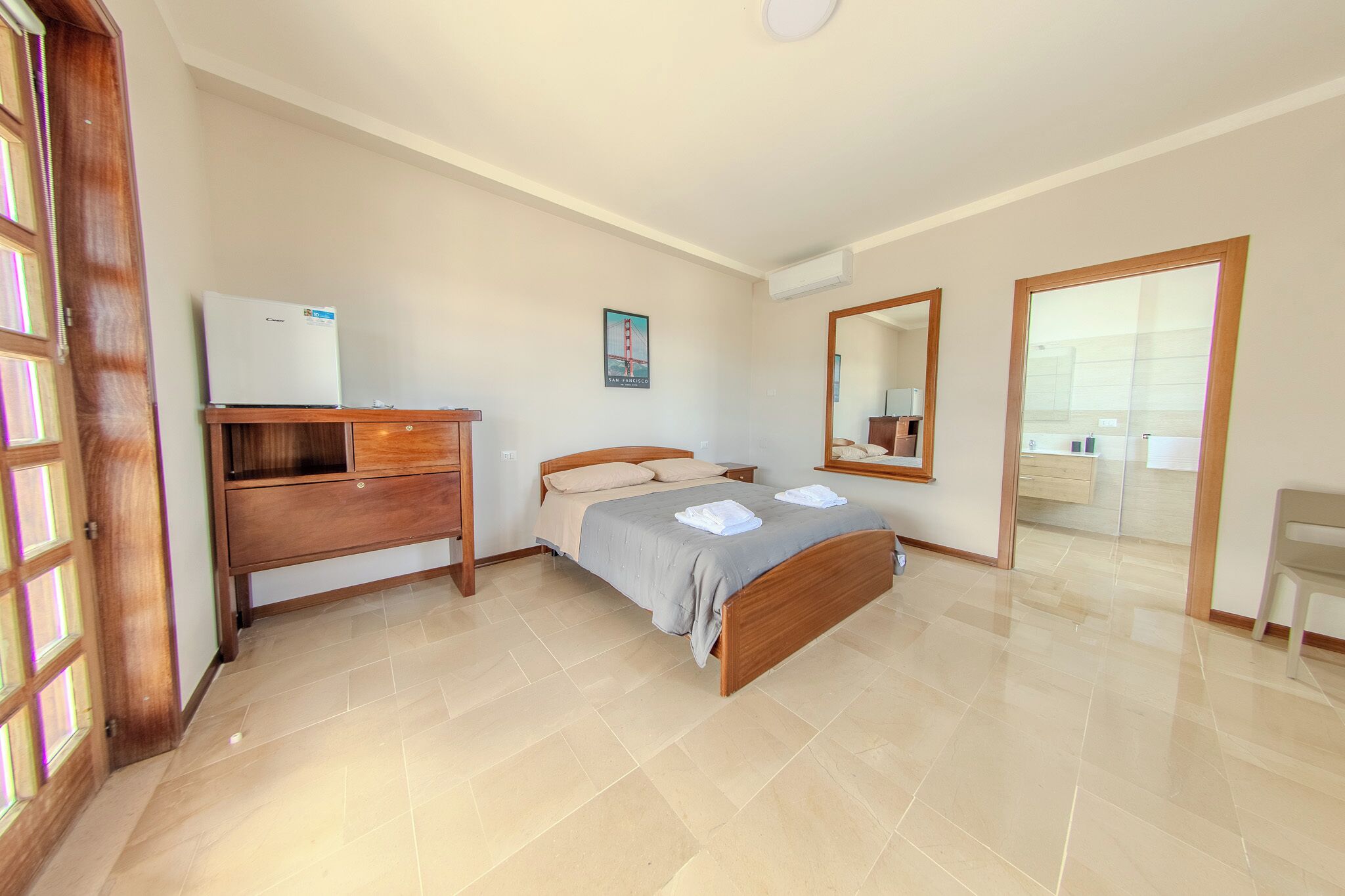Ein Schlafzimmer mit Bett, Kommode, Spiegel und Kühlschrank.