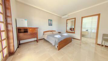 Ein Schlafzimmer mit Bett, Kommode, Spiegel und Kühlschrank.