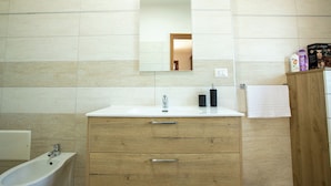 A bathroom with a white sink, wooden cabinet, and a mirror.