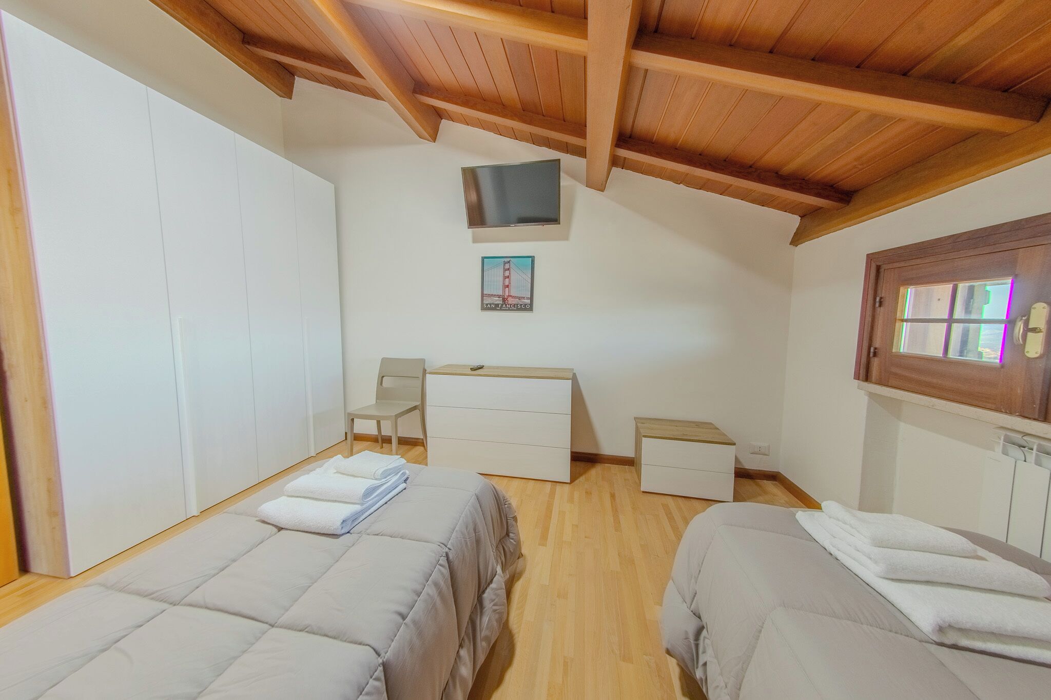 Une chambre avec deux lits, un bureau, une chaise, une télévision et une fenêtre donnant sur le pont du Golden Gate.