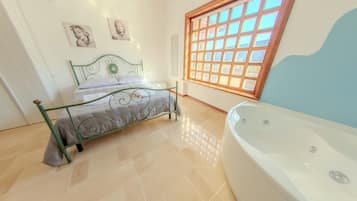Un dormitorio con estructura de cama metálica, un ventanal con diseño de cuadrícula y una bañera blanca.