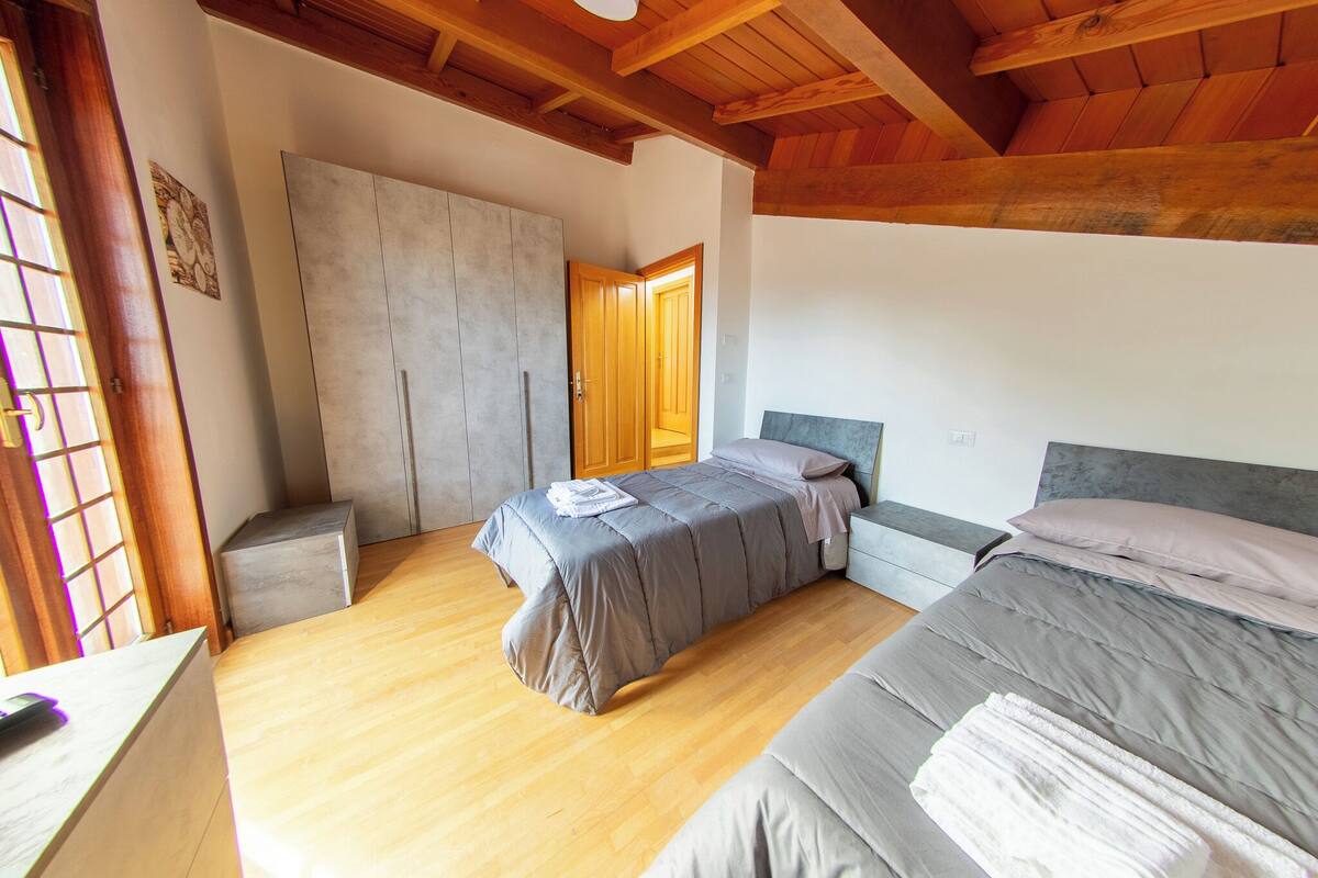 Ein Schlafzimmer mit zwei Betten, Holzboden, einem Kleiderschrank und einer Tür zu einem anderen Raum.