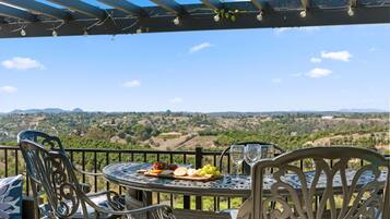Terraço com mesa posta para refeição, com vista para uma paisagem deslumbrante.