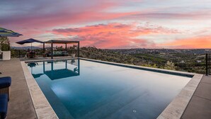 Une piscine avec vue sur le paysage, un espace salon couvert et du mobilier d’extérieur.
