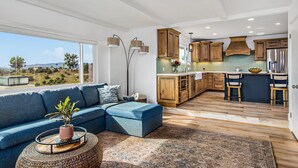 Une cuisine moderne avec des meubles en bois, un grand îlot central et une vue sur l’extérieur.