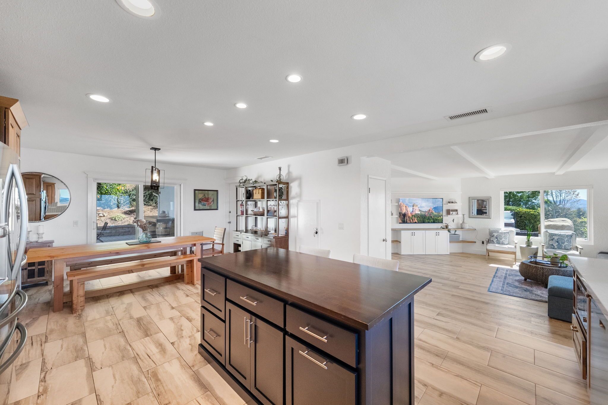 A spacious kitchen with a central island, wooden flooring, and white cabinetry.