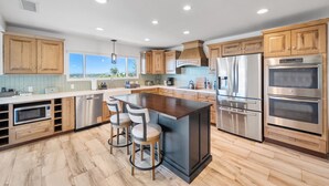 Une cuisine moderne avec des meubles en bois, des appareils en acier inoxydable et un grand îlot central doté de tabourets.