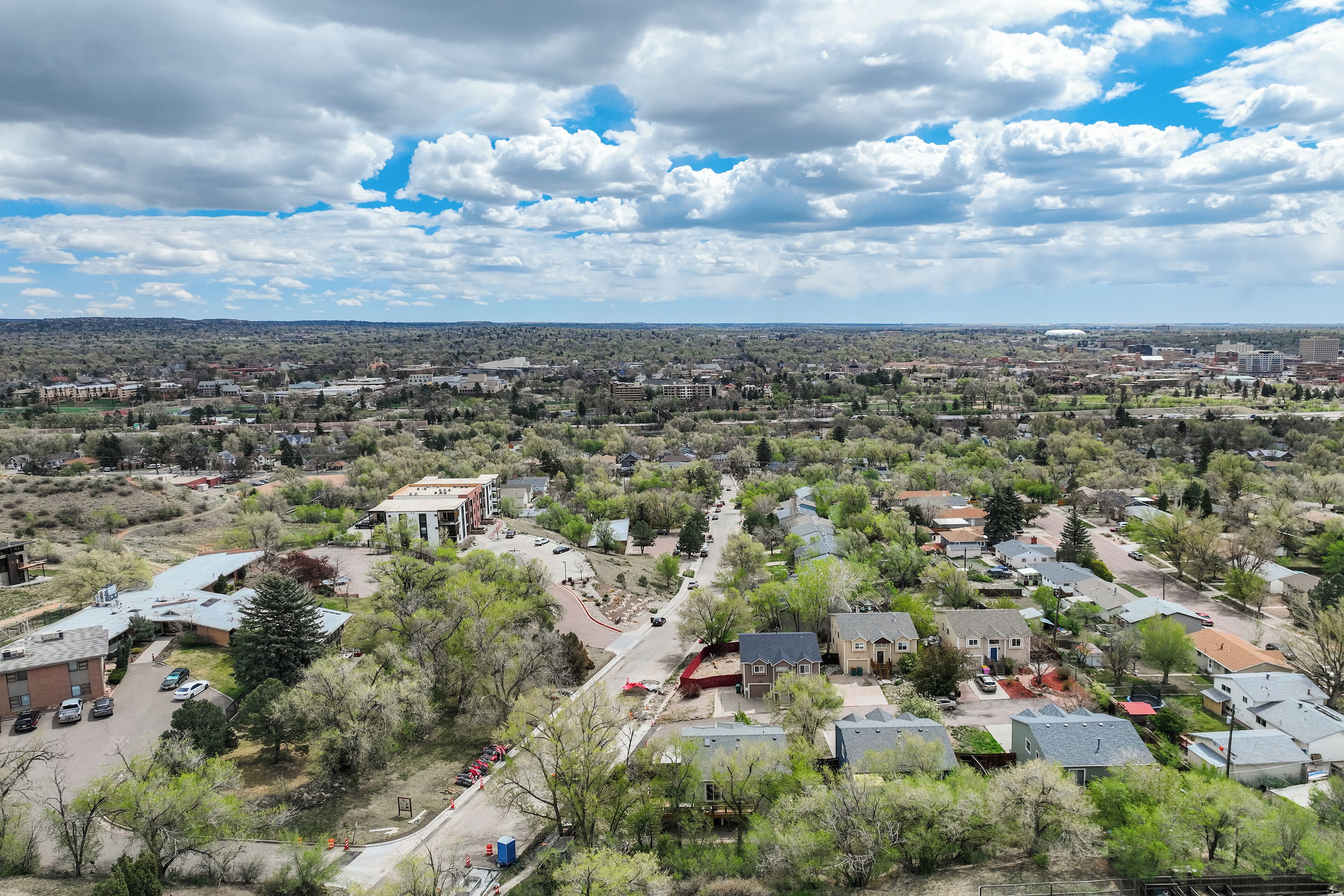 An aerial view of a residential area with houses, roads, and a distant stadium.