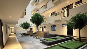 Un patio interior moderno con una zona de estar central, varios niveles con balcones y un largo pasillo.