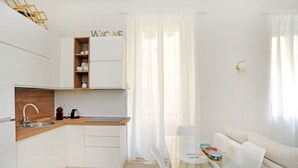 A modern kitchen with white cabinetry, a wooden countertop, and a built-in shelf. - Corsica Apartment Travel Inside  (MILANO)