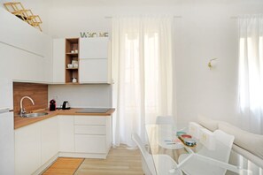 A modern kitchen with white cabinetry, a wooden countertop, and a built-in shelf.
