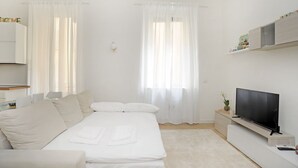 A modern bedroom with a bed, a TV, and a small table. - Corsica Apartment Travel Inside  (MILANO)
