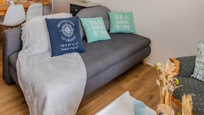 A cozy living room with a grey sofa, a dining table with chairs, and a small side table with a lamp. - Le Cottage*Côte Sauvage*Plage*Shops*Parking (Le Croisic)