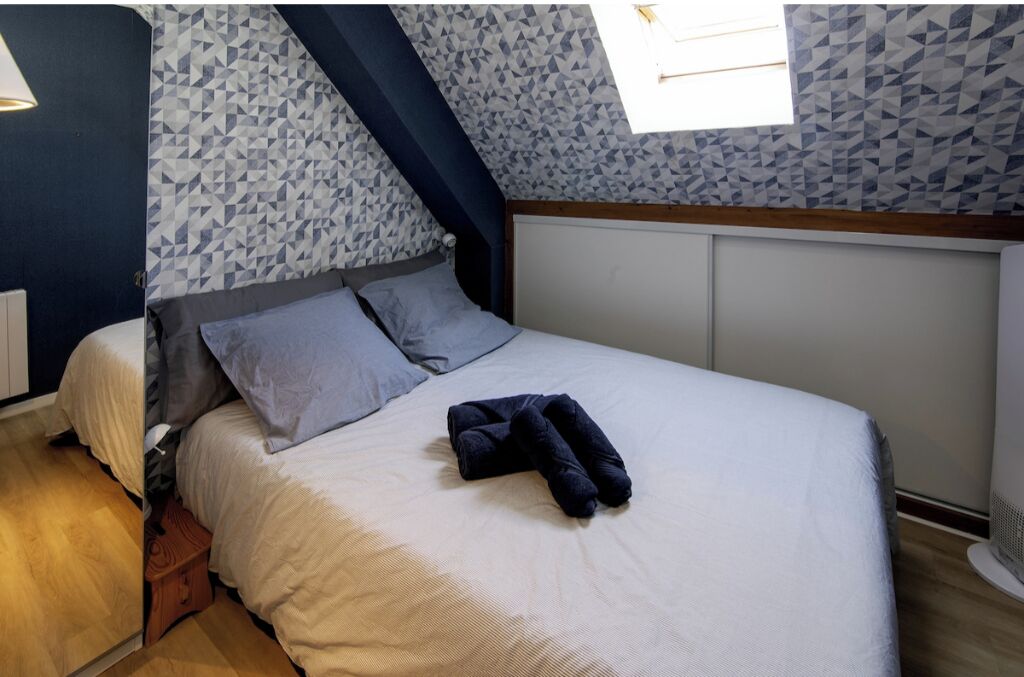 Quarto com cama, almofadas e toalha dobrada.