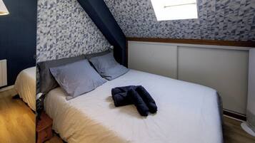 Quarto com cama, almofadas e toalha dobrada.