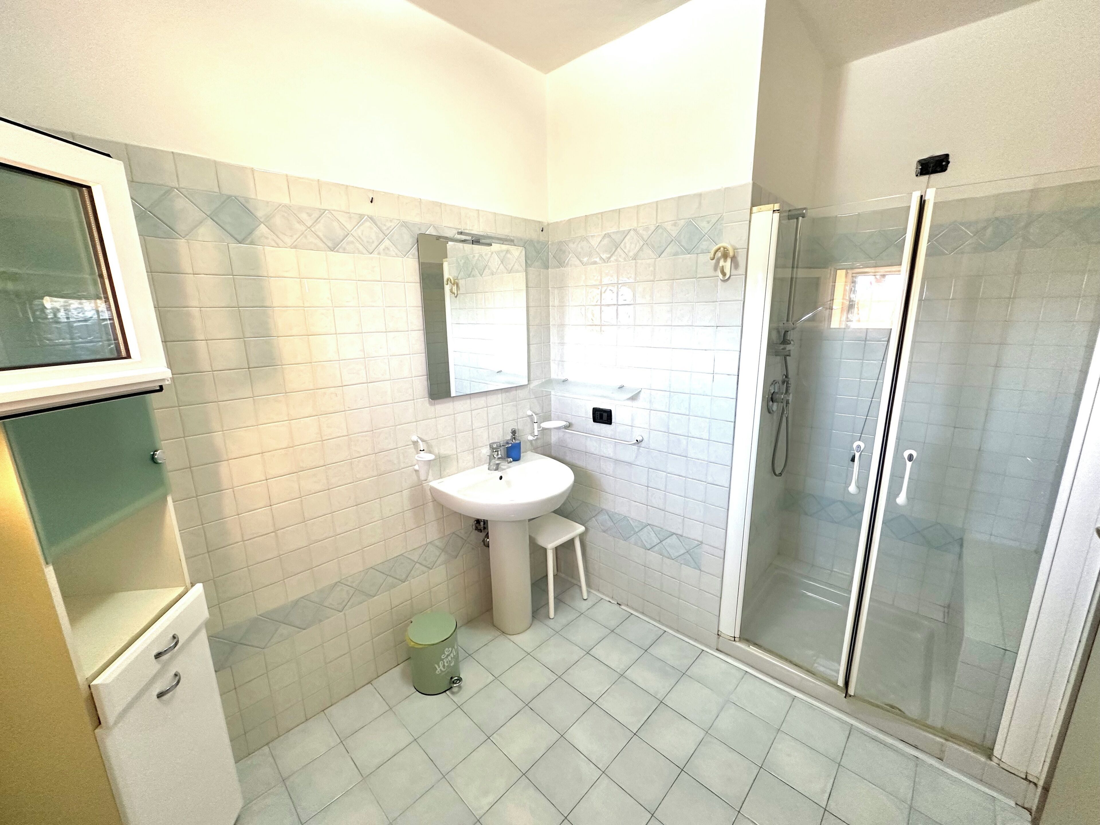 A bathroom with a sink, mirror, and shower.