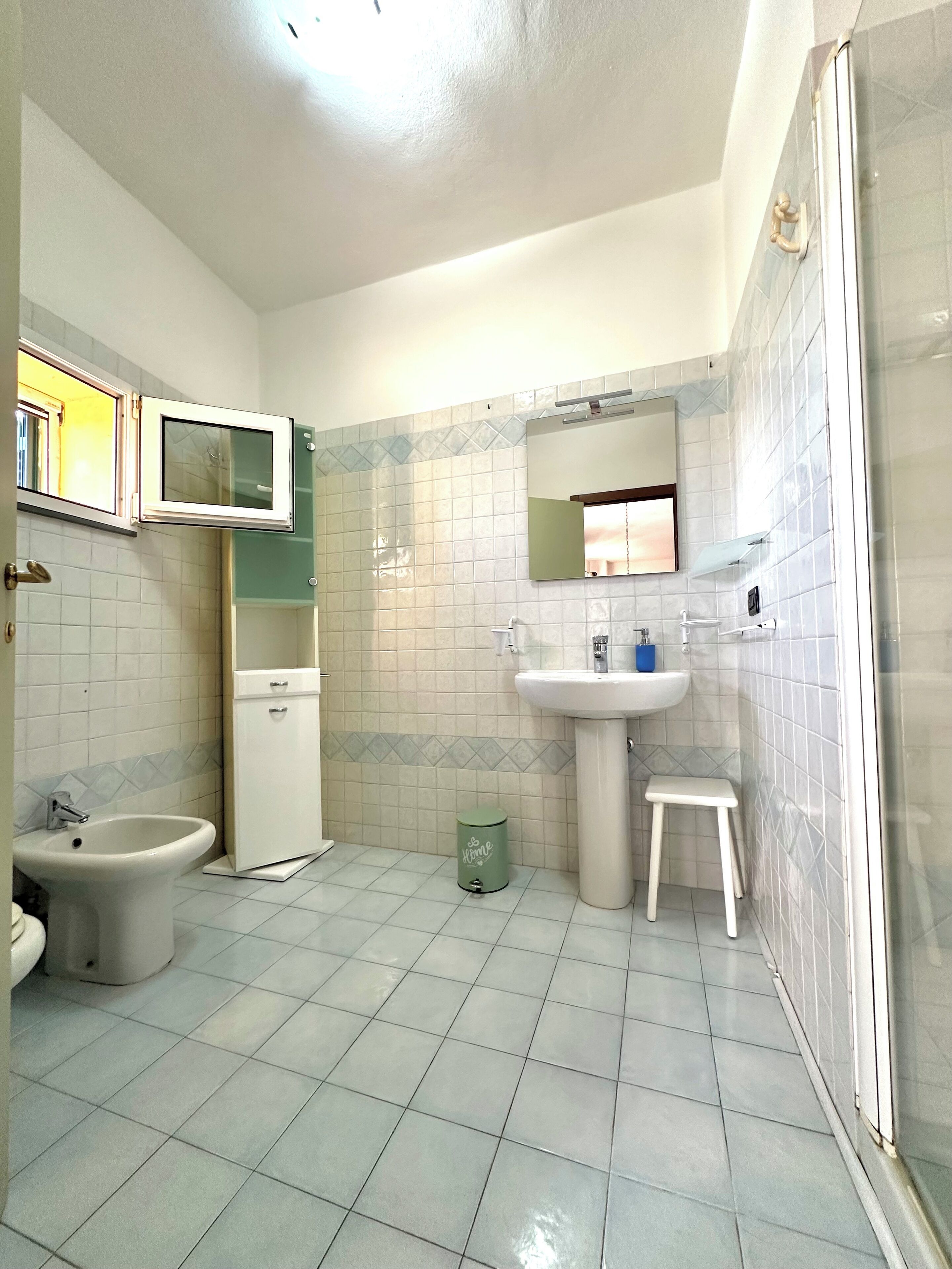 Ein Badezimmer mit Toilette, Bidet, Waschbecken und einem kleinen Hocker.