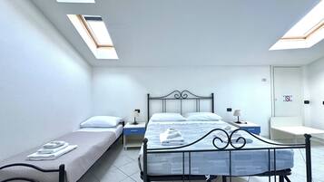Ein Zimmer mit zwei Betten, einem Schreibtisch und einem Stuhl. Im Deckenbereich befinden sich Dachfenster.