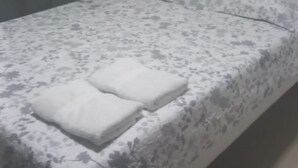 A bed with a floral-patterned bedspread and two pillows, a grey headboard, and a grey curtain. - Nice Apartment 3 (Cartagena de Indias)