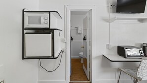 A compact kitchenette with a microwave, toaster, and a TV mounted on the wall. - Atomic #1 I Downtown I Historic I Trailer Parking (Moab)
