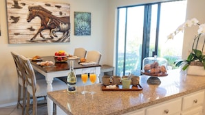 A kitchen with a granite countertop, a dining table with chairs, a bottle of wine, glasses, and a fruit bowl. - Kiler Ranch House is a charming 3-bedroom house that is ideal for a weekend away (Paso Robles)