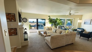A spacious living room with a large sofa, a coffee table, and a view of the outdoors through large windows. - Kiler Ranch House is a charming 3-bedroom house that is ideal for a weekend away (Paso Robles)
