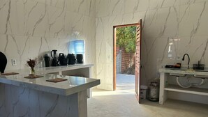 A modern kitchen with marble countertops, a coffee machine, and a water dispenser. - Casa da Paz  (Trairi)