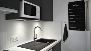 A modern kitchen with a built-in microwave, a stainless steel sink, and a blackboard with daily menu items. - Nice T2 on the little port of Sanary, Clim (Sanary-sur-Mer)