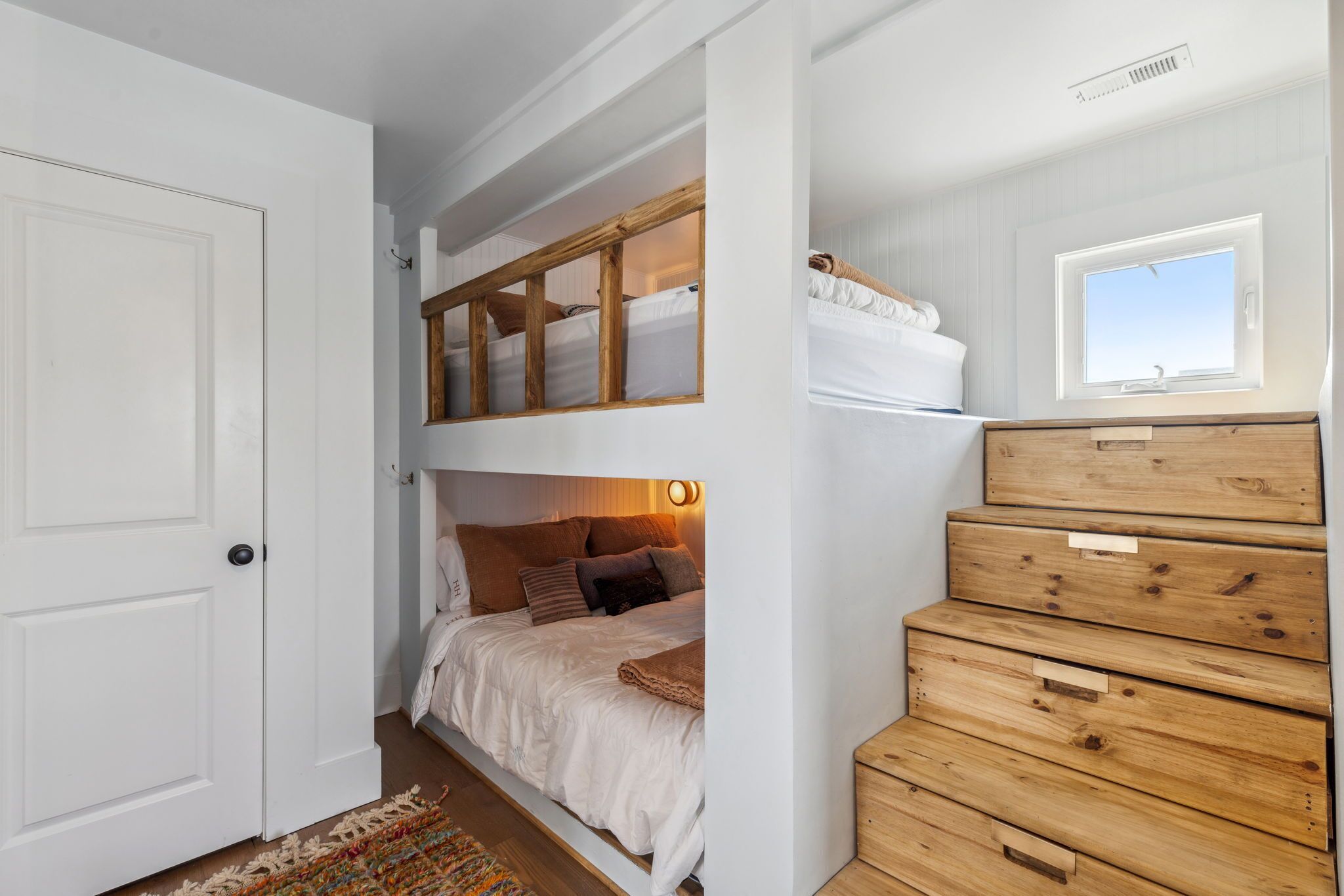 A room with a bunk bed, a wooden dresser, and a window.