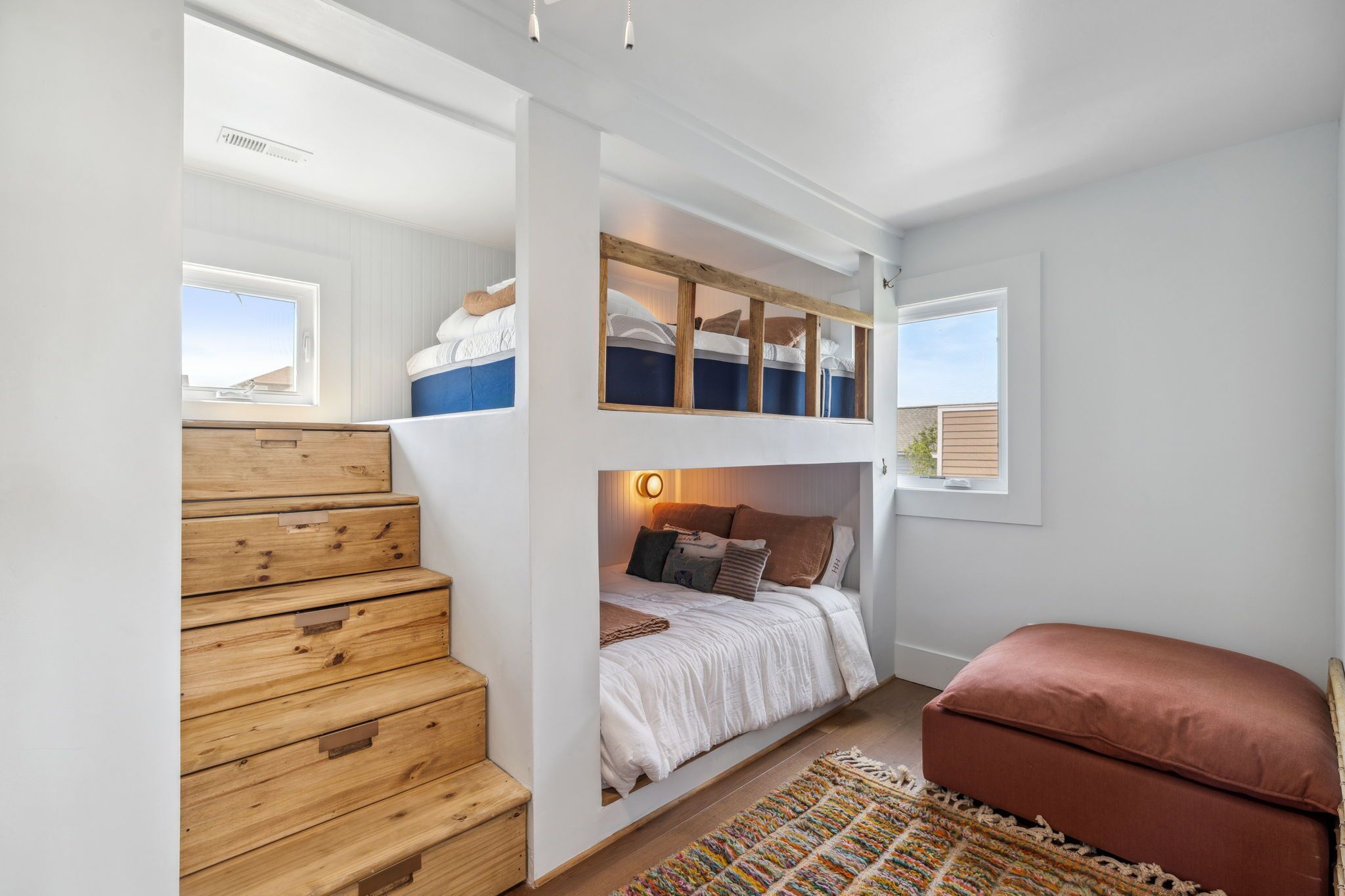 Una habitación con literas, una escalera de madera y una pequeña zona de estar.